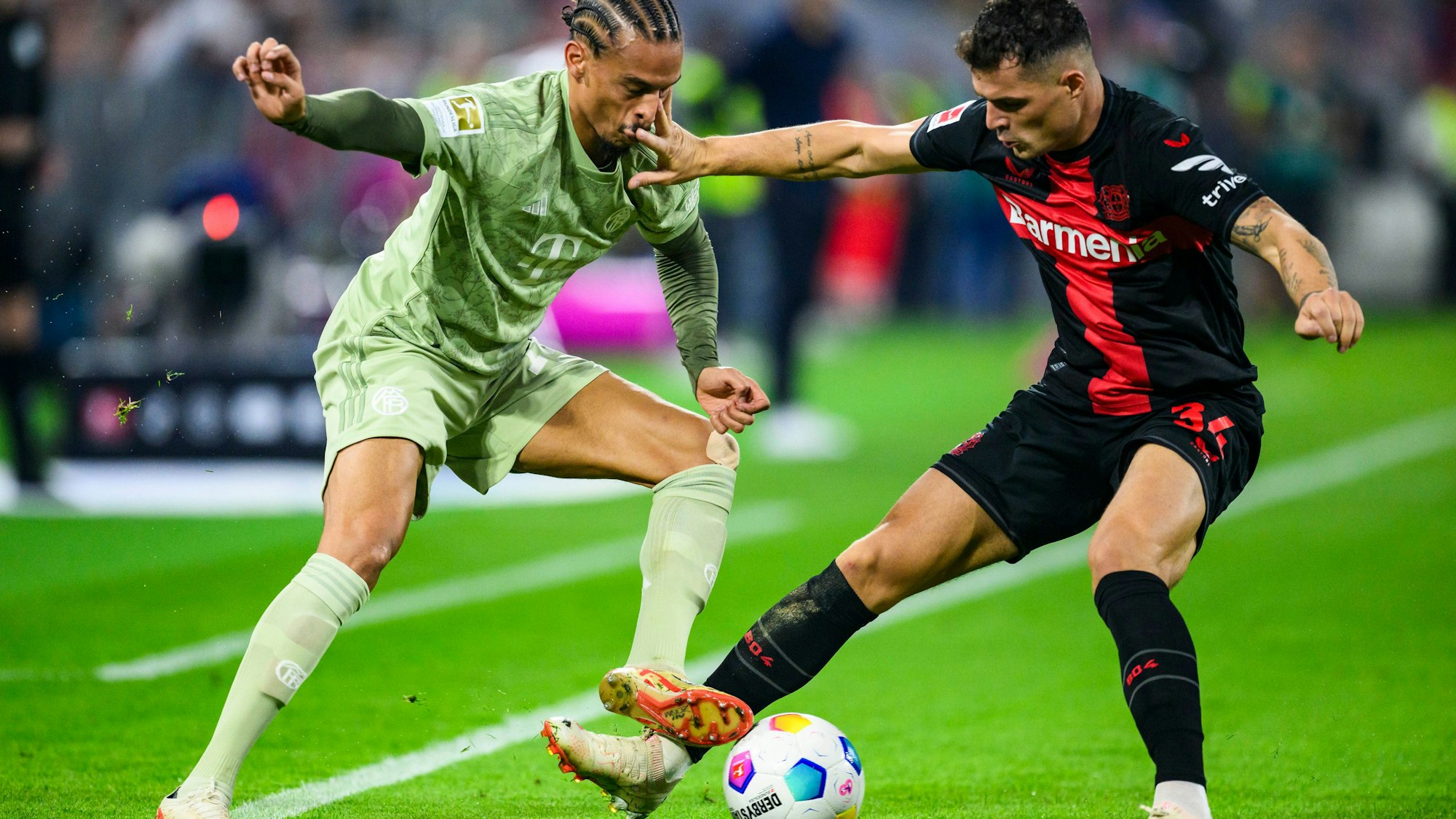 Münchens Leroy Sane (l) in Aktion gegen Leverkusens Granit Xhaka (r). Am Samstag treffen Leverkusen und München zum Topspiel des 21. Spieltags aufeinander.