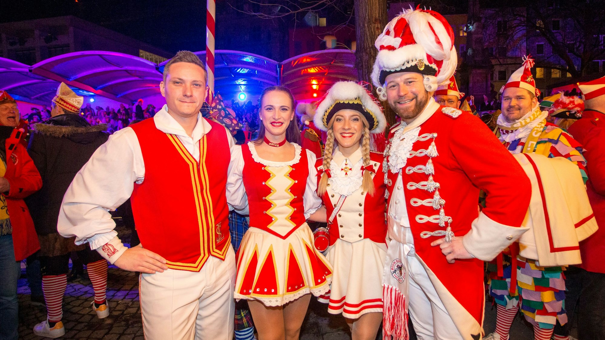 Zwei Tanzpaare grinsen in rot-weißen Kostümen in die Kamera.