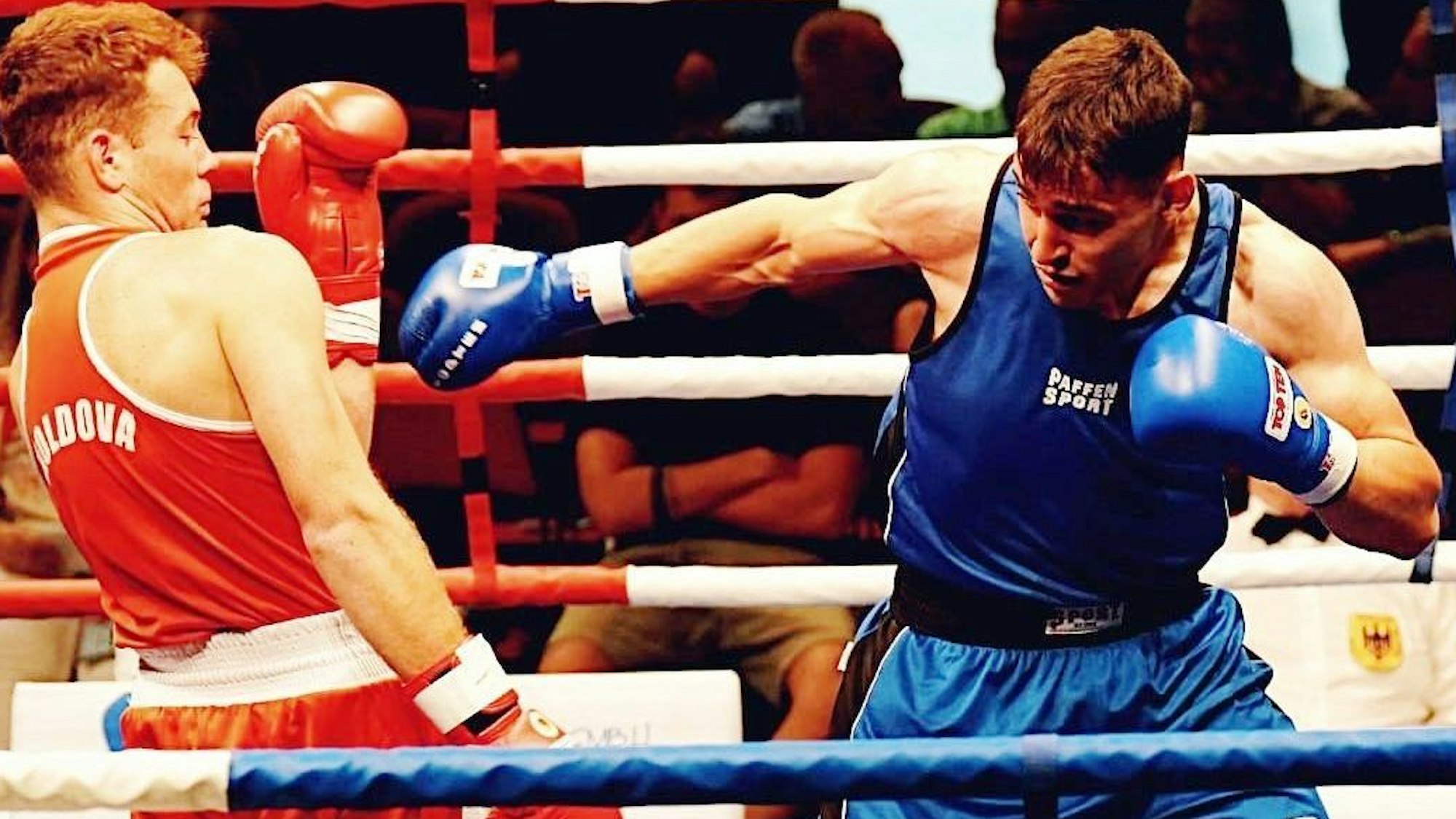 Jason Zeller in Blau boxt gegen einen Gegner in Rot.