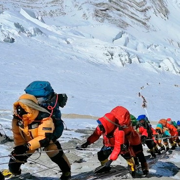 In einer langen Schlange klettern Bergsteiger auf einem Pfad knapp unterhalb von Lager vier.