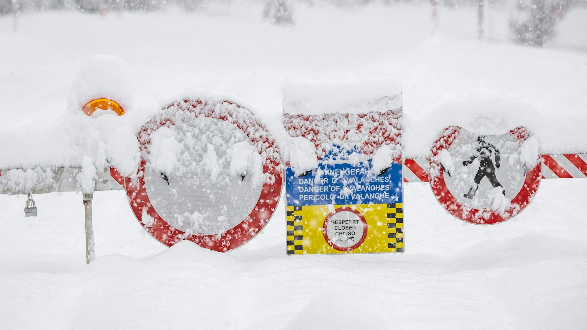 Eine Straßensperre mit mehreren Warnschildern blockiert eine Straße in den Alpen. Starker Schneefall kommt am Wochenende auf Österreich, die Schweiz und Italien zu. (Symbolbild)