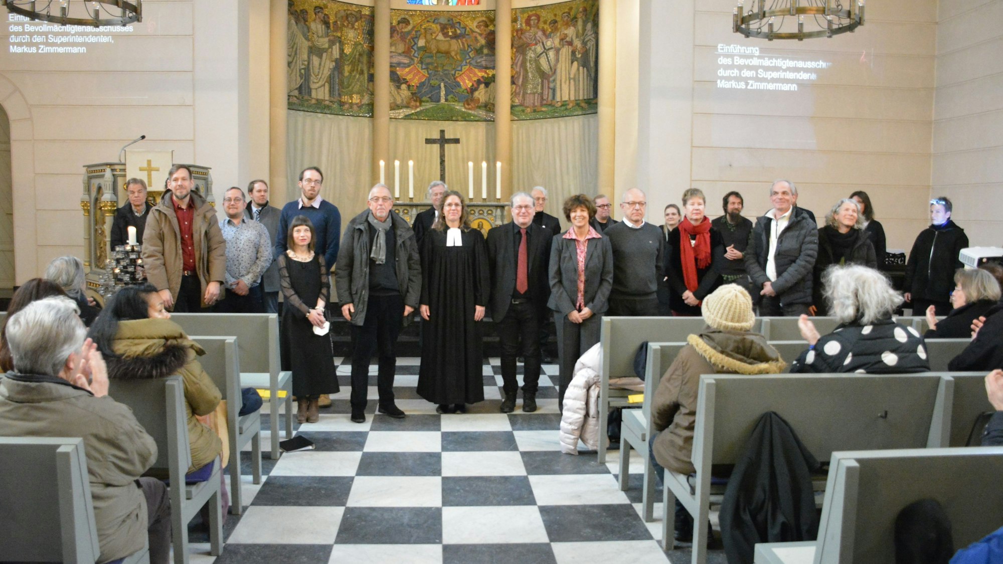 Männer und Frauen stehen vor dem Altar in der evangelischen Friedenskirche.