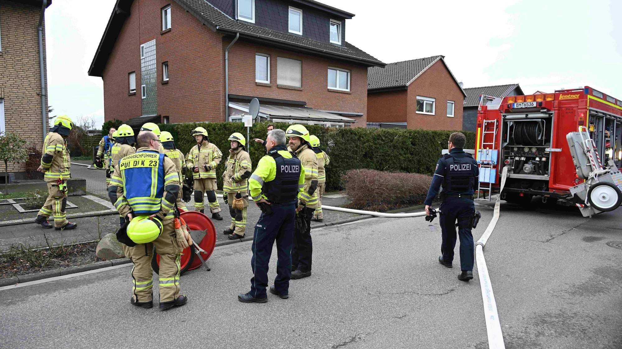 Das Bild zeigt mehrere Einsatzkräfte von Polizei und Feuerwehr vor einem Wohnhaus.