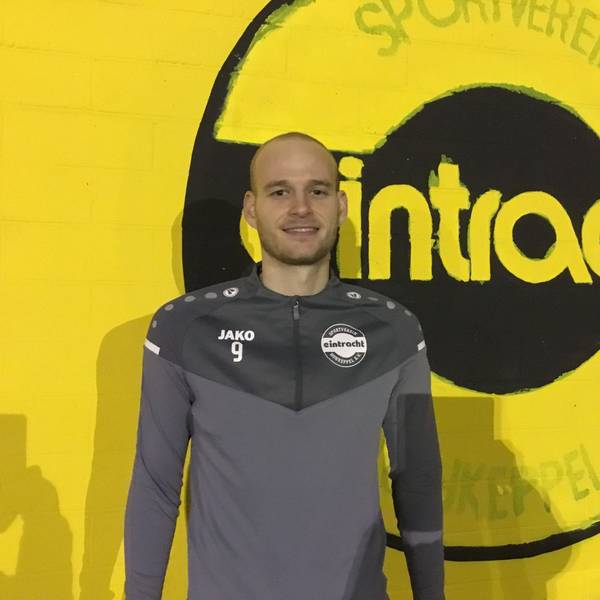 Fußballer Jannes Hoffmann steht vor einer gelben Wand mit dem Schriftzug „Eintracht“.
