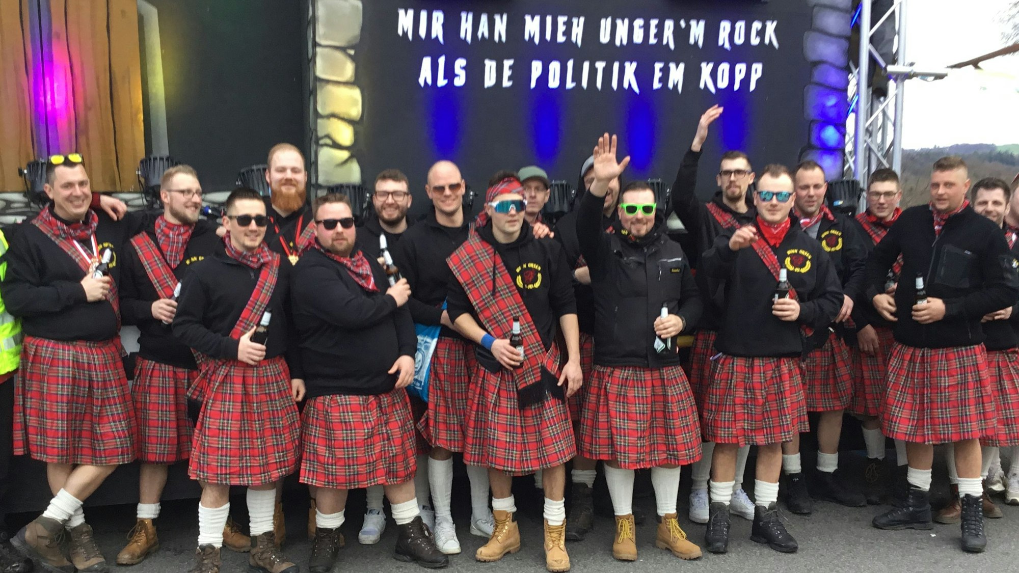 Eine Gruppe steht in Schottenröcken vor einer Halle.