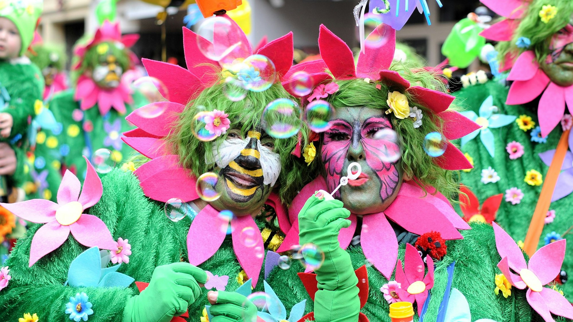 Als Blumenwiese verkleidete Menschen machen Seifenblasen.