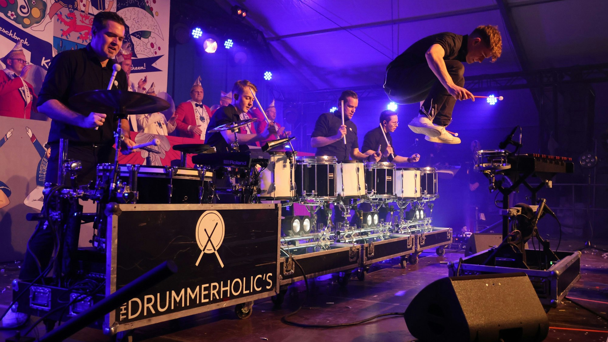 Ein Mann einer Band springt auf der Bühne in die Höhe.