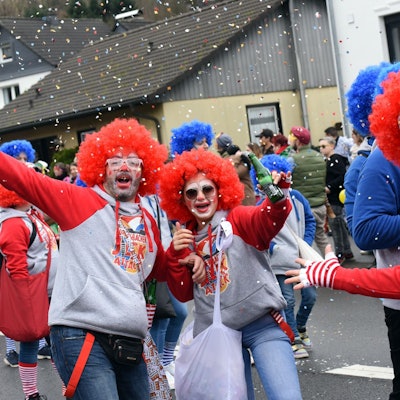 Mehrere Leute sind als Clowns verkleidet und schießen Konfetti in die Luft.