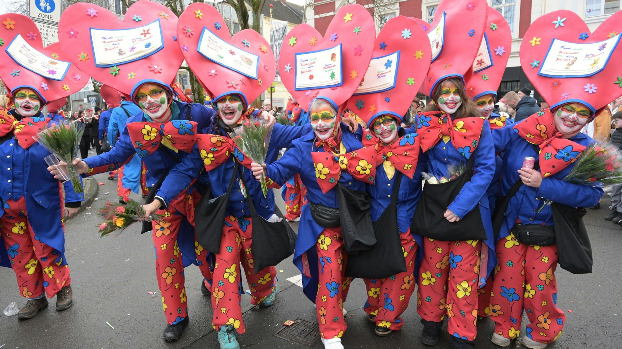 Menschen mit Herzhüten stehen in einer Reihe.
