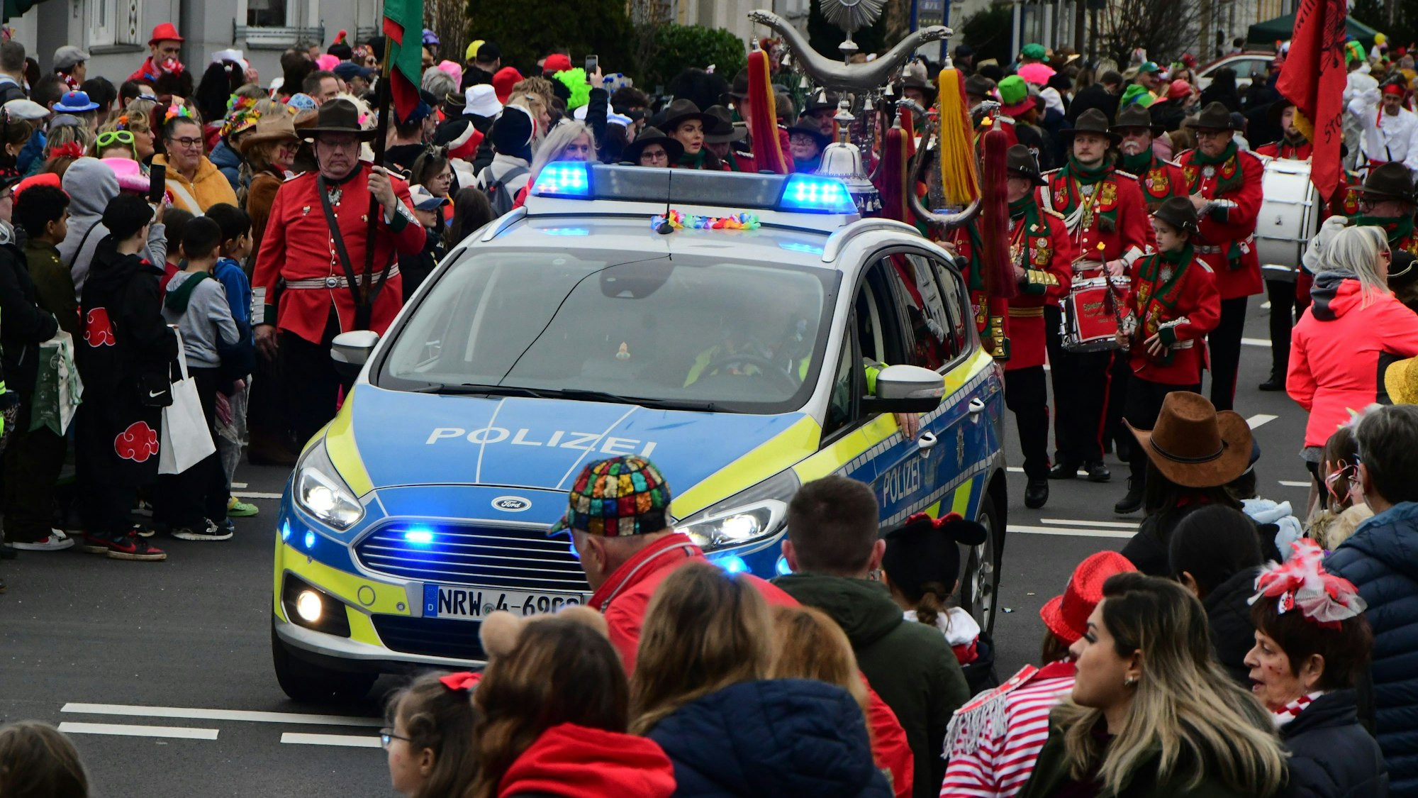 Ein Polizeiauto rollt an der Spitze des Südstadtzugs in Euskirchen, Zuschauer säumen die Straßenränder.