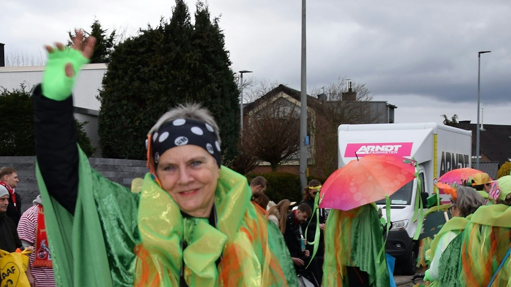 Eine Frau winkt in die Kamera.