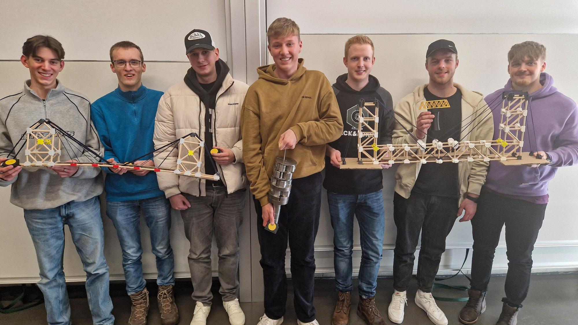 Gruppenfoto einer Studentengruppe. Diese präsentiert eine selbstgebaute Brückenkonstruktion.