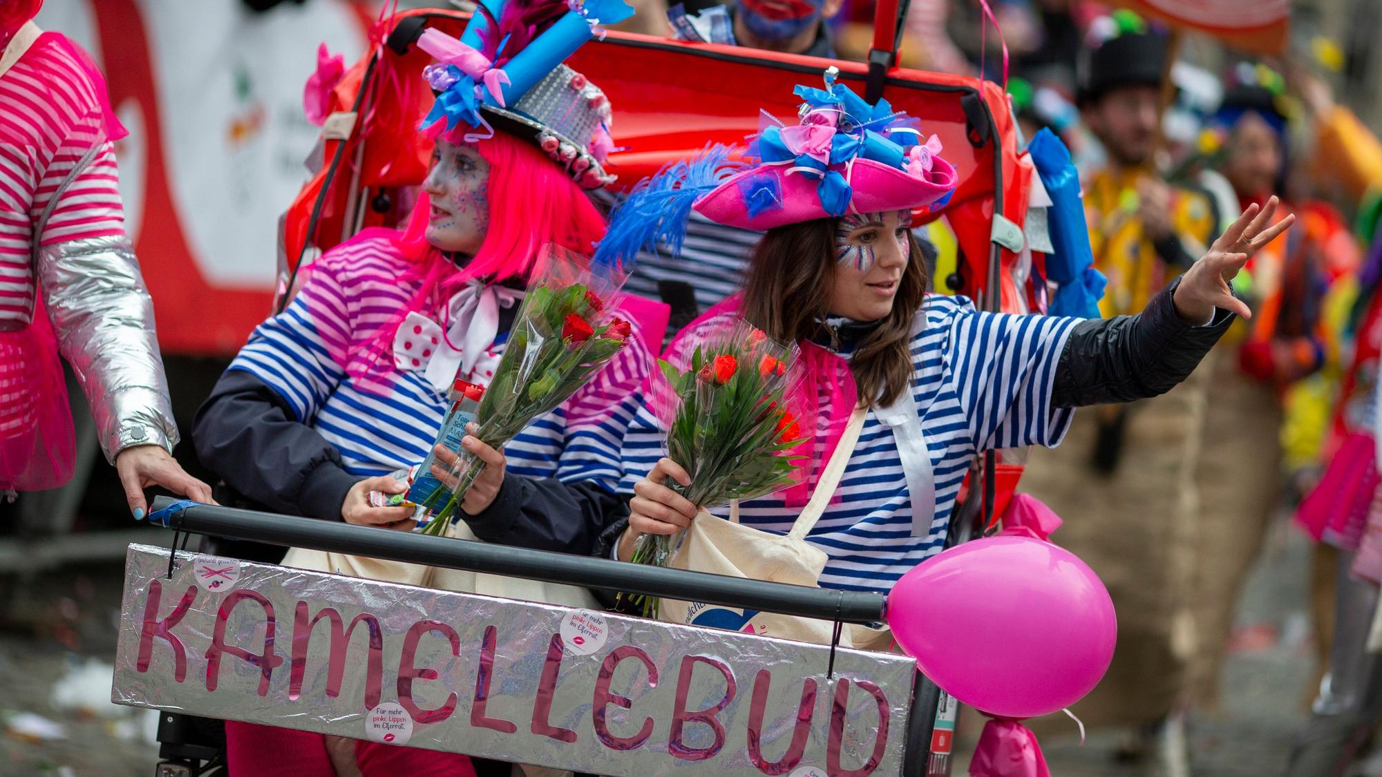 Zwei kostümierte Frauen in einer selbstgebauten „Kamellebud“ gehen bei den Schull- un Veedelszöch mit.