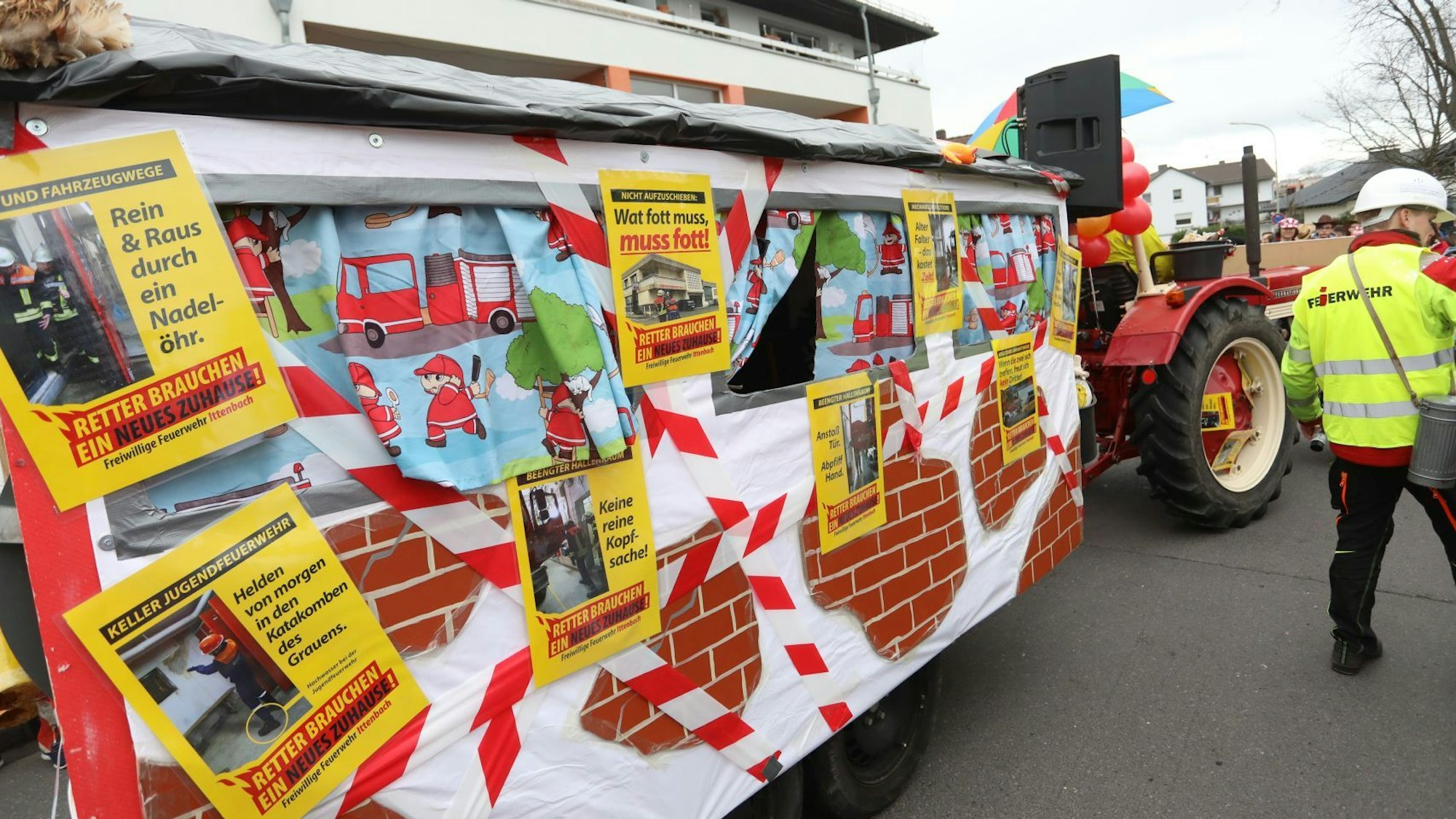 Ein Karnevalswagen mit Fotos und Schildern, auf denen die Feuerwehr die misslichen Zustände im Gerätehaus deutlich macht.