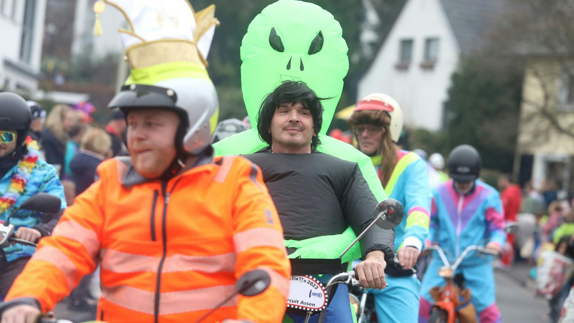 Mehrere Männer fahren hintereinander auf ihren Mofas an den Zuschauern vorbei.
