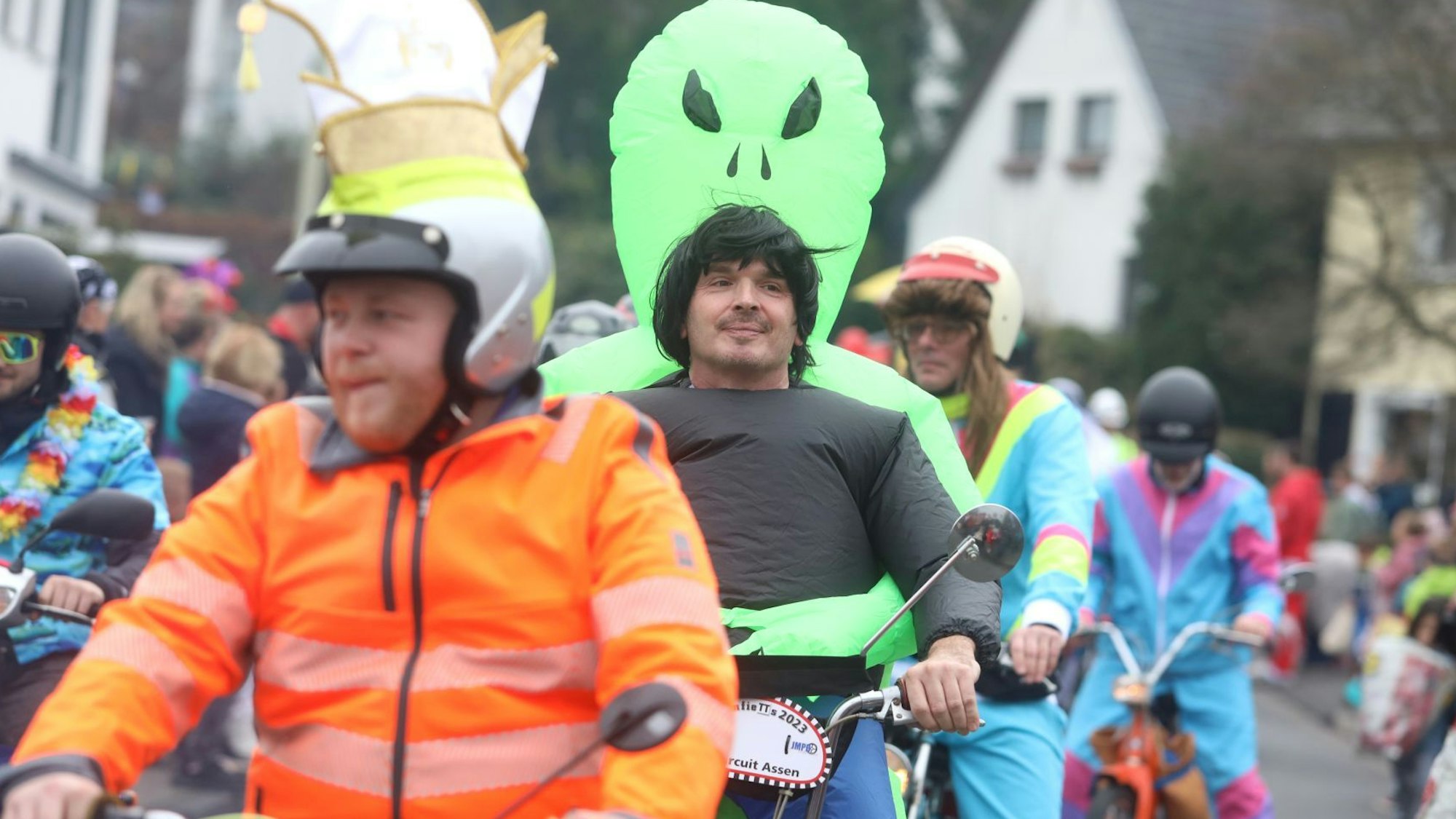 Mehrere Männer fahren hintereinander auf ihren Mofas an den Zuschauern vorbei.