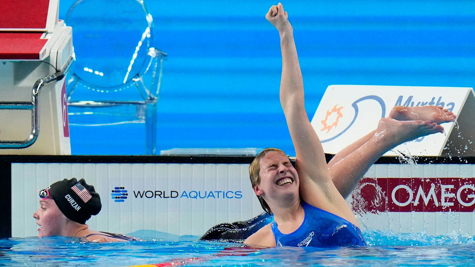 Angelina Kohler of Germany, right, celebrates after winning in the women's 100m Butterfly Final at the World Aquatics Championships in Doha, Qatar, Monday, Feb. 12, 2024. At left is Claire Curzan of the United States who came in second place. (AP Photo/Hassan Ammar)