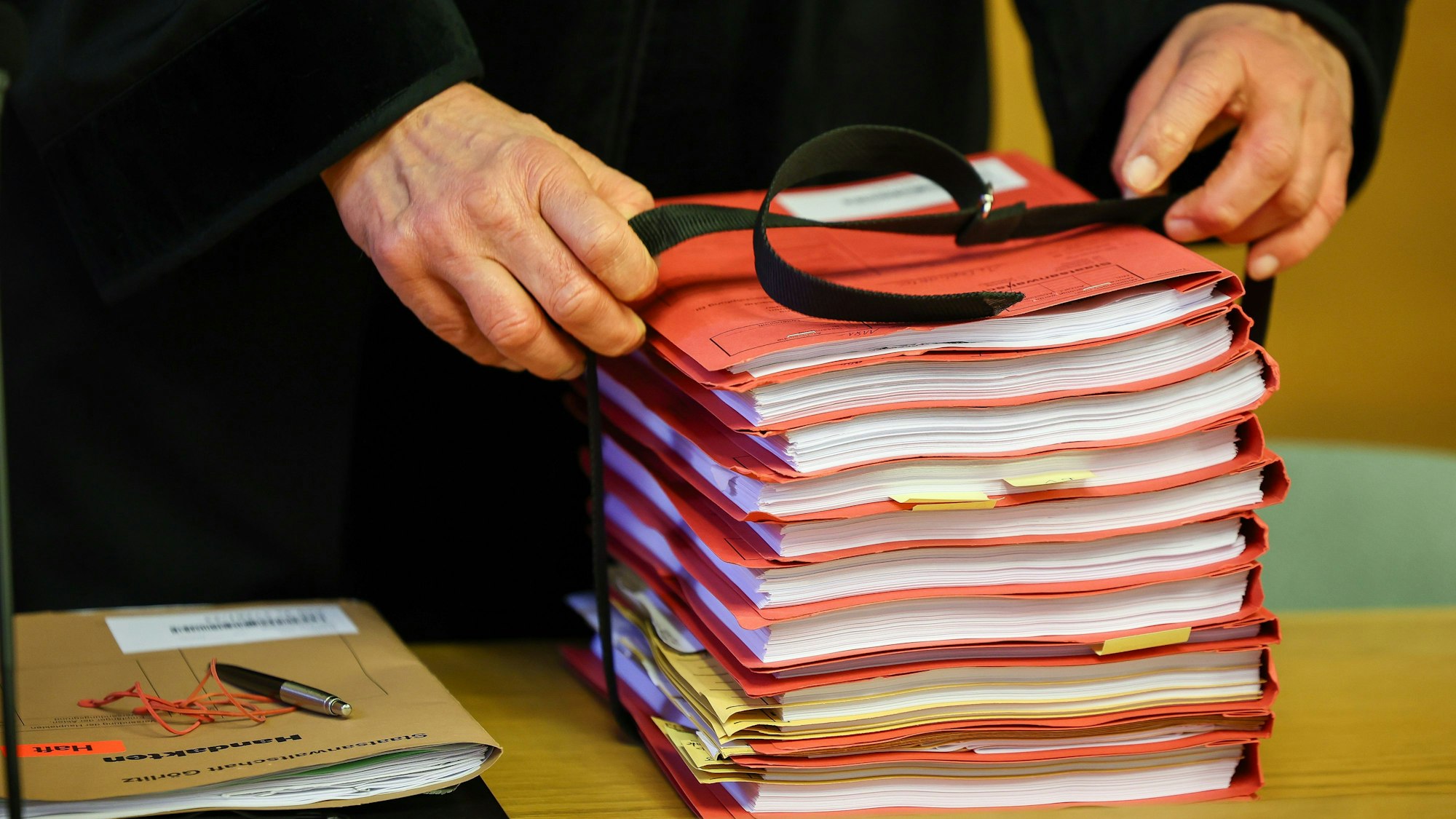 Der Staatsanwalt legt einen Stapel Akten vor Prozessbeginn auf seinen Tisch.