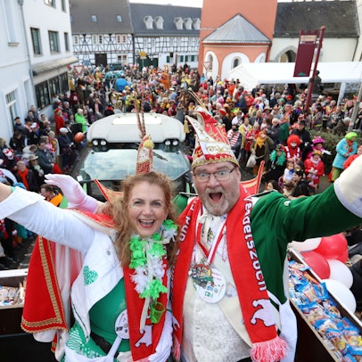 Das neue Prinzenpaar hoch oben auf dem Prinzenwagen, im Hintergrund zahlreiche kostümierte Jecken auf der Straße.