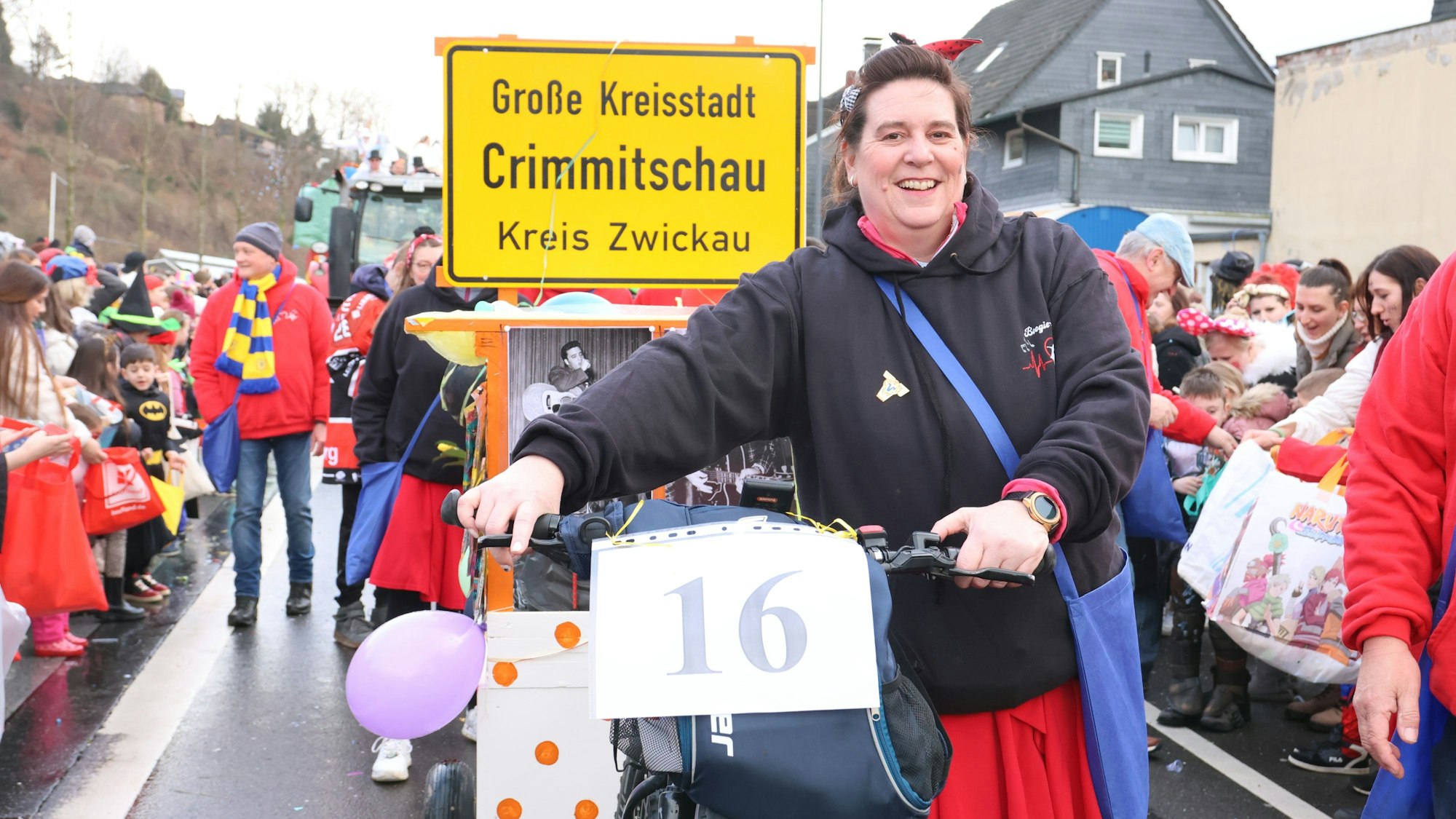 Eine Frau zieht einen Anhänger mit einem gelben Ortsschild.