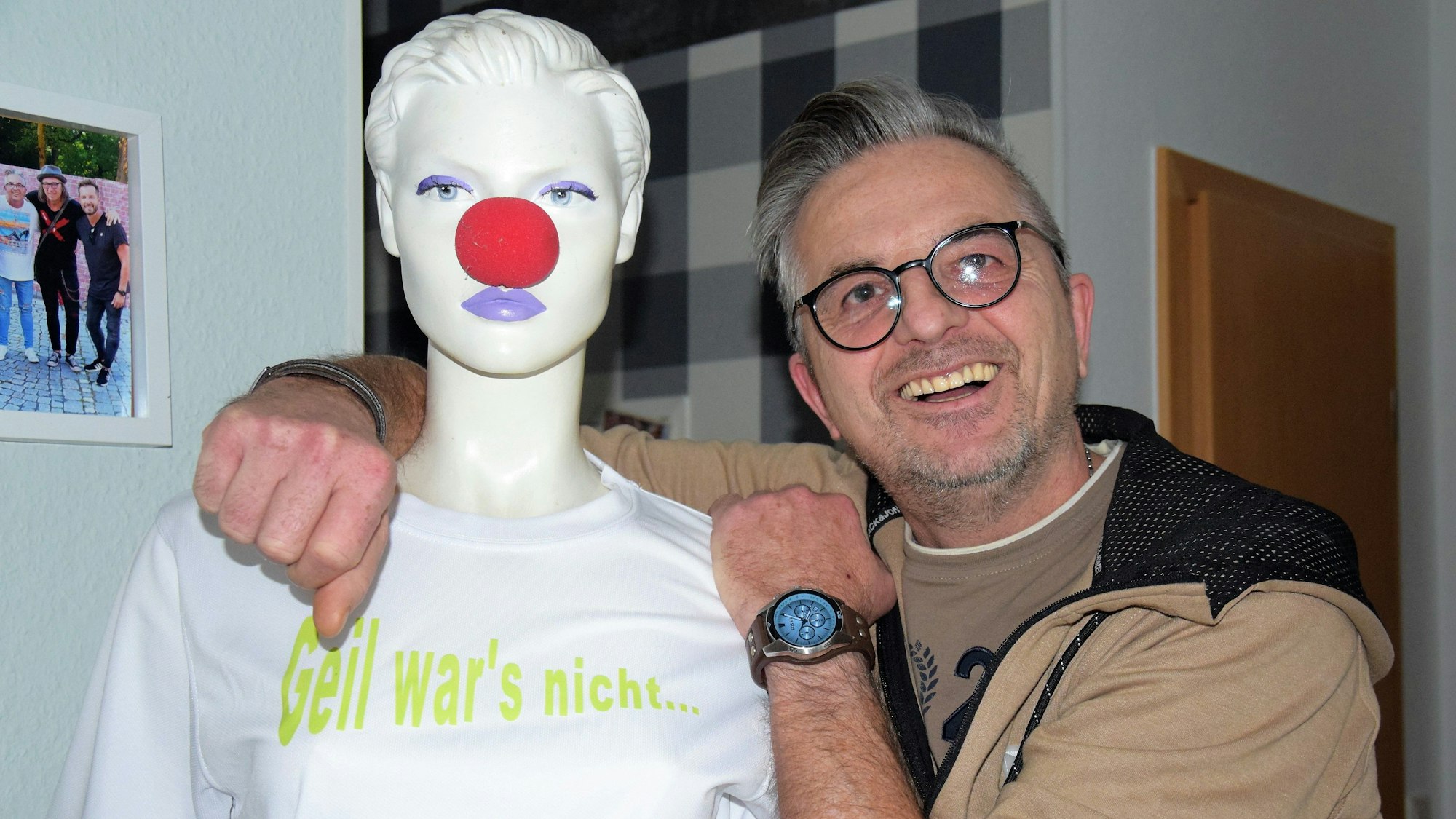 Auf dem Foto ist Ingo Stromberg zu sehen. Er lehnt sich an eine Schaufensterpuppe an, die eine rote Pappnase trägt.