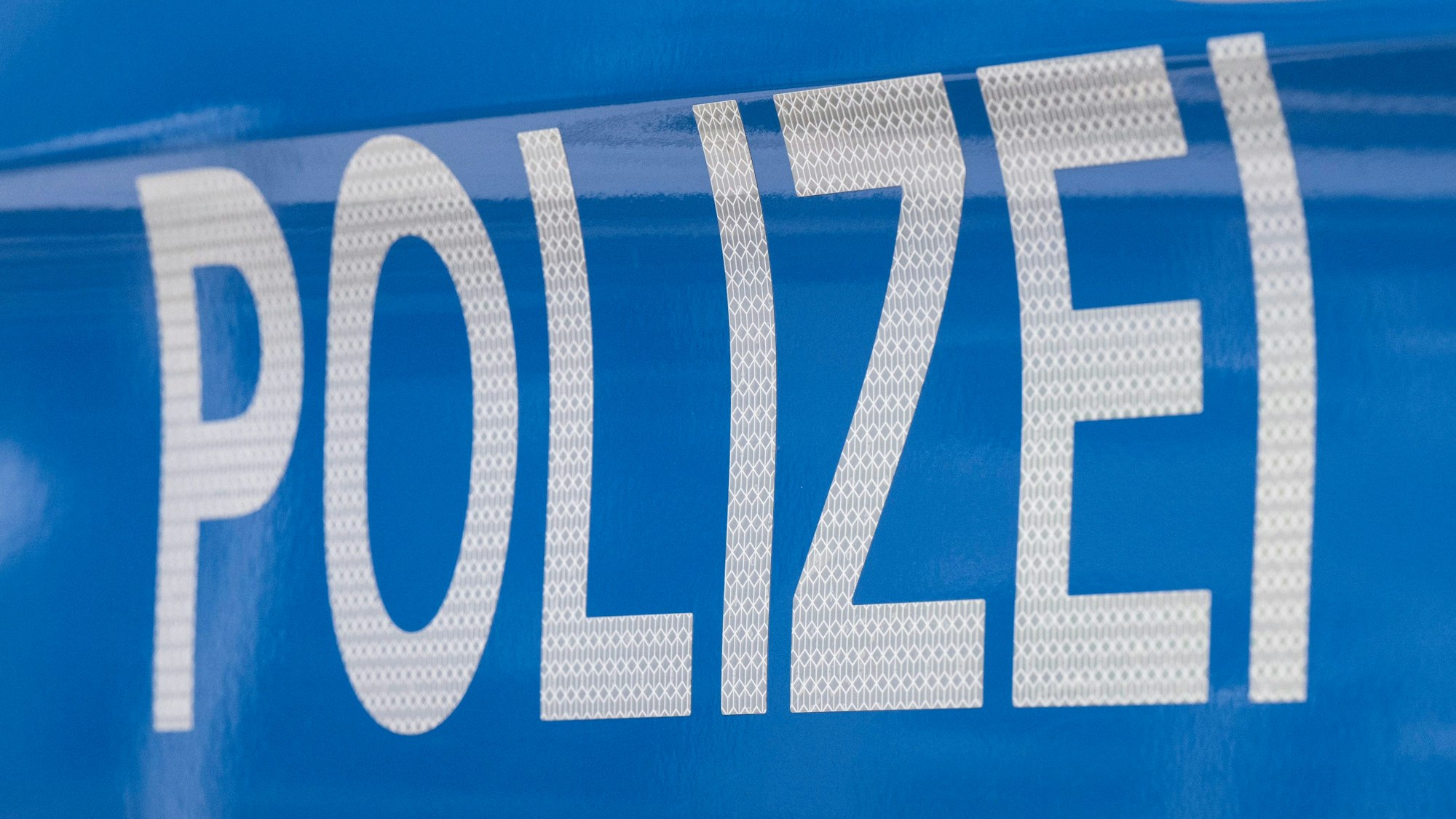 Der Schriftzug „Polizei“ ist auf einem Streifenwagen zu lesen.