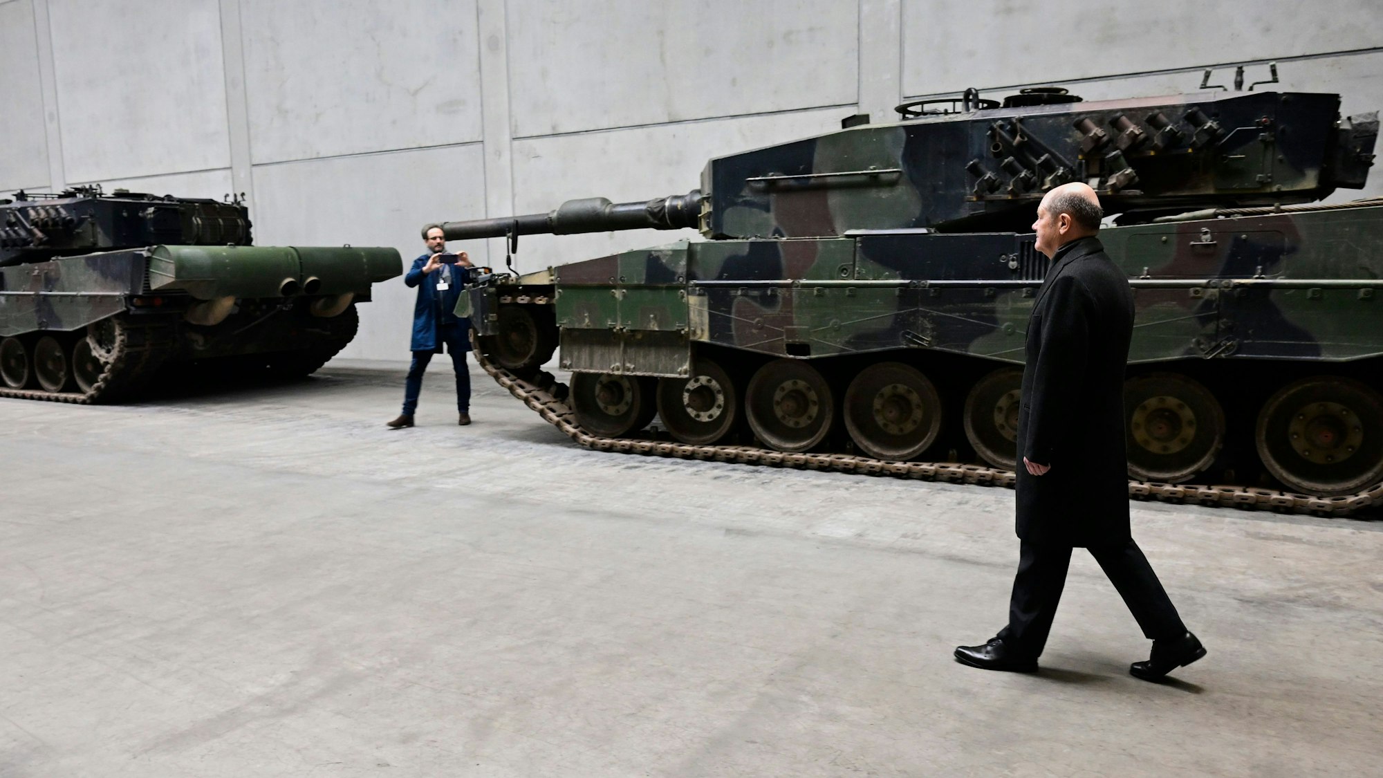 Olaf Scholz (r.) steht vor einem Leopard-Panzer. Der Bundeskanzler ist zu einem symbolischen Spatenstich und der Einweihung des neuen Rheinmetall-Werks ins niedersächsische Unterlüß gekommen.