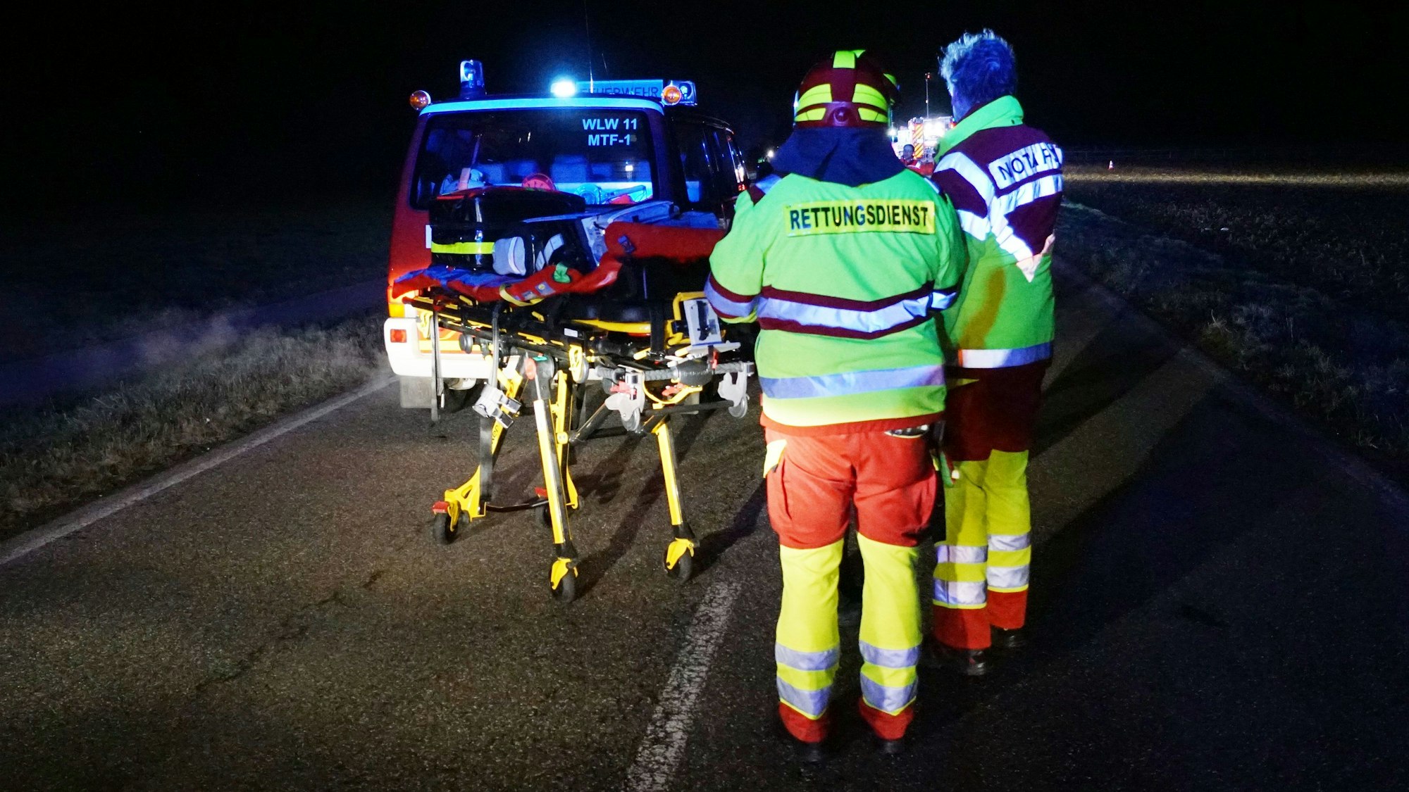 Das Bild zeigt zwei Rettungsdienstmitarbeiter an der Unfallstelle am Karnevalssonntag. Im Hintergrund steht ein Feuerwehrauto.