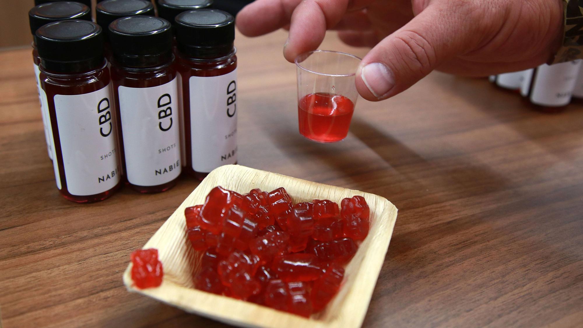 Cannabis-Gummibärchen und CBD-Shots stehen bei einer Hanf-Messe auf einem Tisch. In Russland ist ein Deutscher mit Gummibärchen dieser Art festgenommen worden.