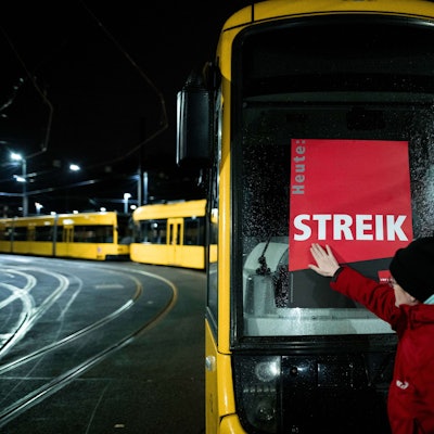 Eine Mitarbeiterin klebt ein Poster, auf dem «STREIK» steht, auf eine Bahn im Depot der Ruhrbahn in Essen.