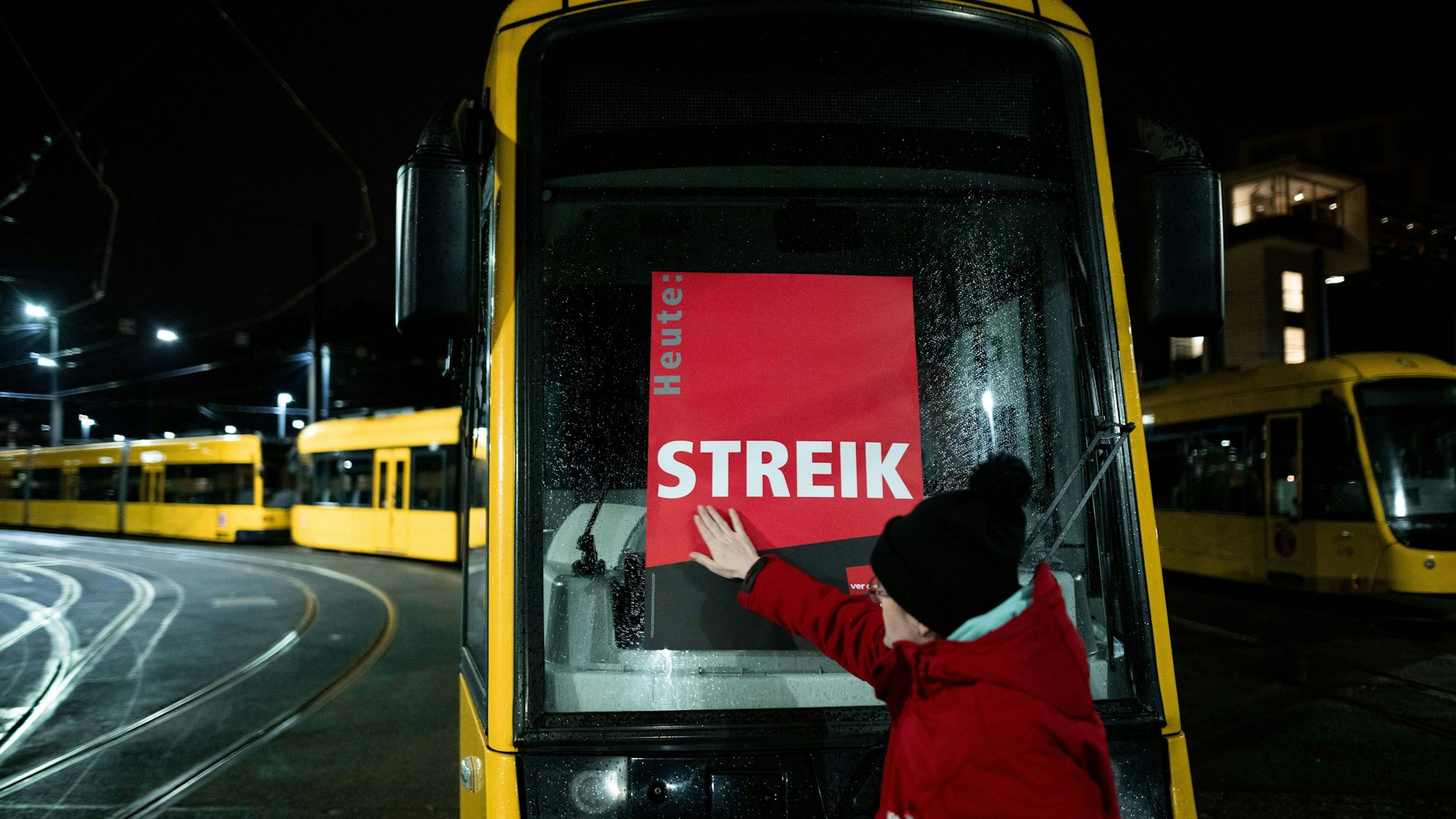 Eine Mitarbeiterin klebt ein Poster, auf dem «STREIK» steht, auf eine Bahn im Depot der Ruhrbahn in Essen.