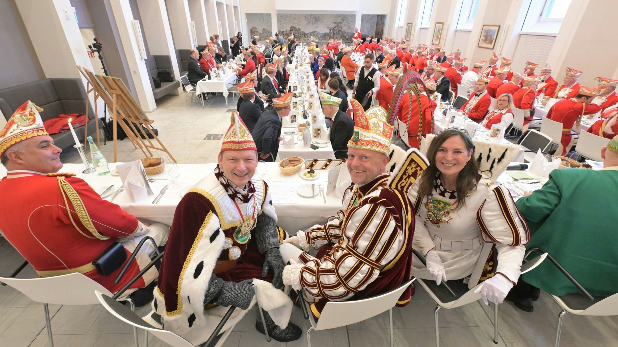 Das Bergisch Gladbacher Dreigestirn sitzt auf dem Podium beim Prinzenessen 2024.