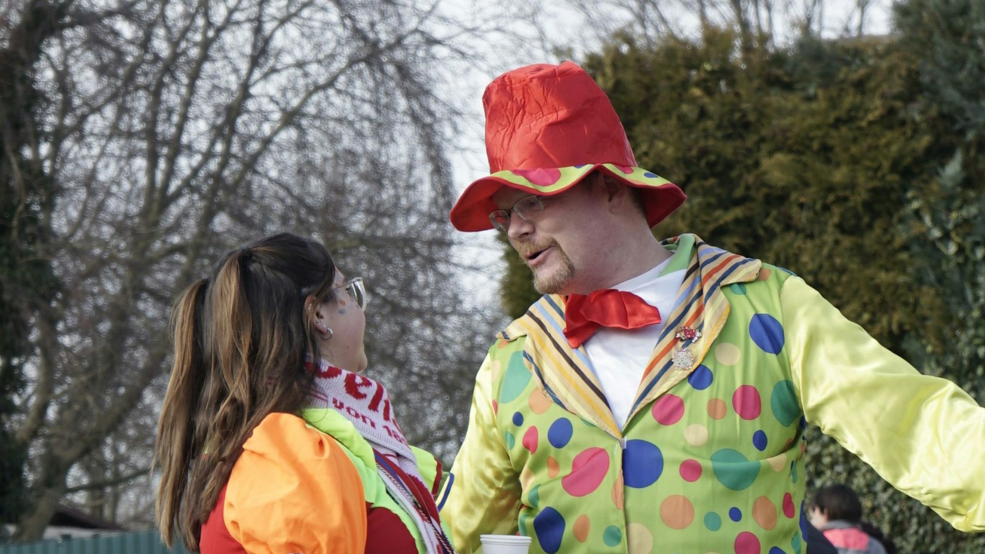 Ein Mann und eine Frau in bunten Kostümen unterhalten sich.
