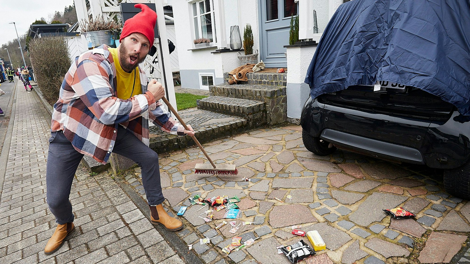 Dominik Stahnke fegt die Spuren des Karnevalszugs in Schleiden zusammen.