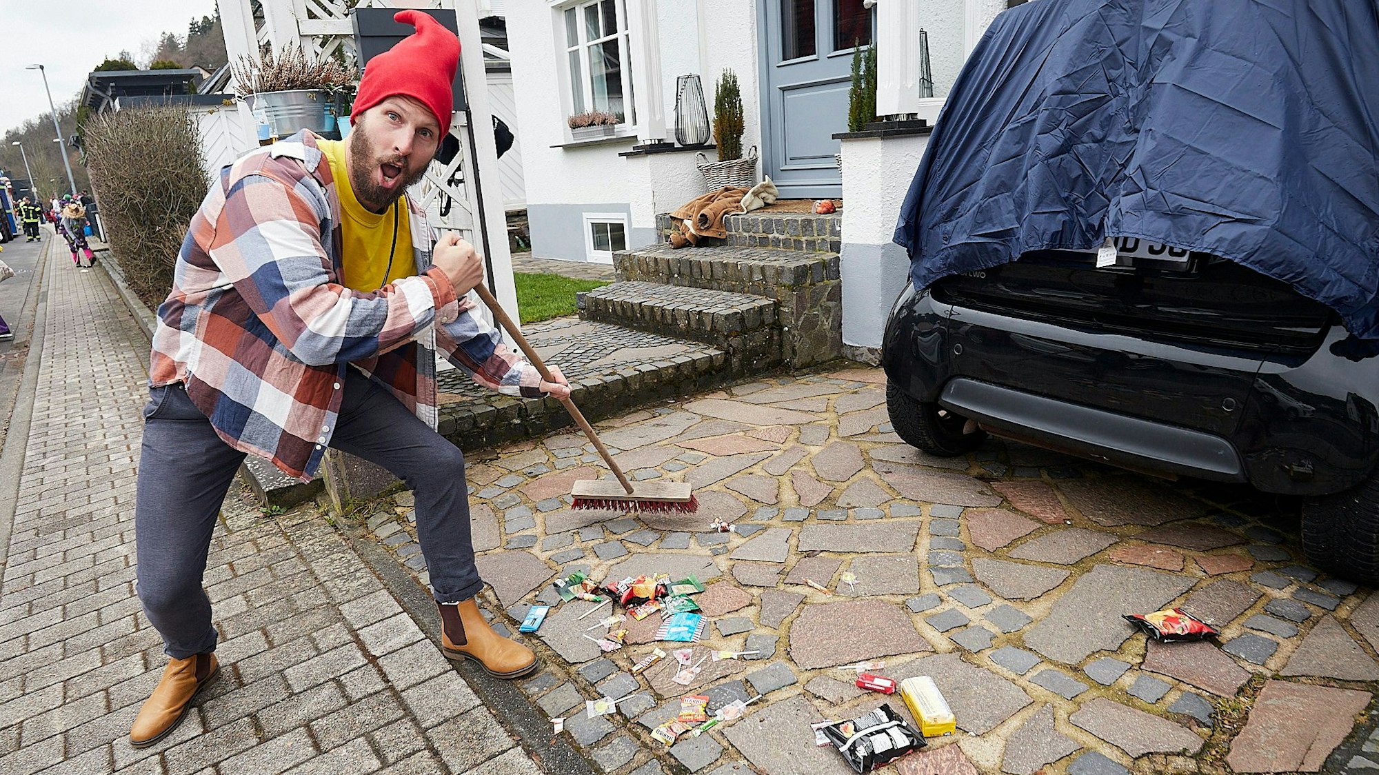 Dominik Stahnke fegt die Spuren des Karnevalszugs in Schleiden zusammen.