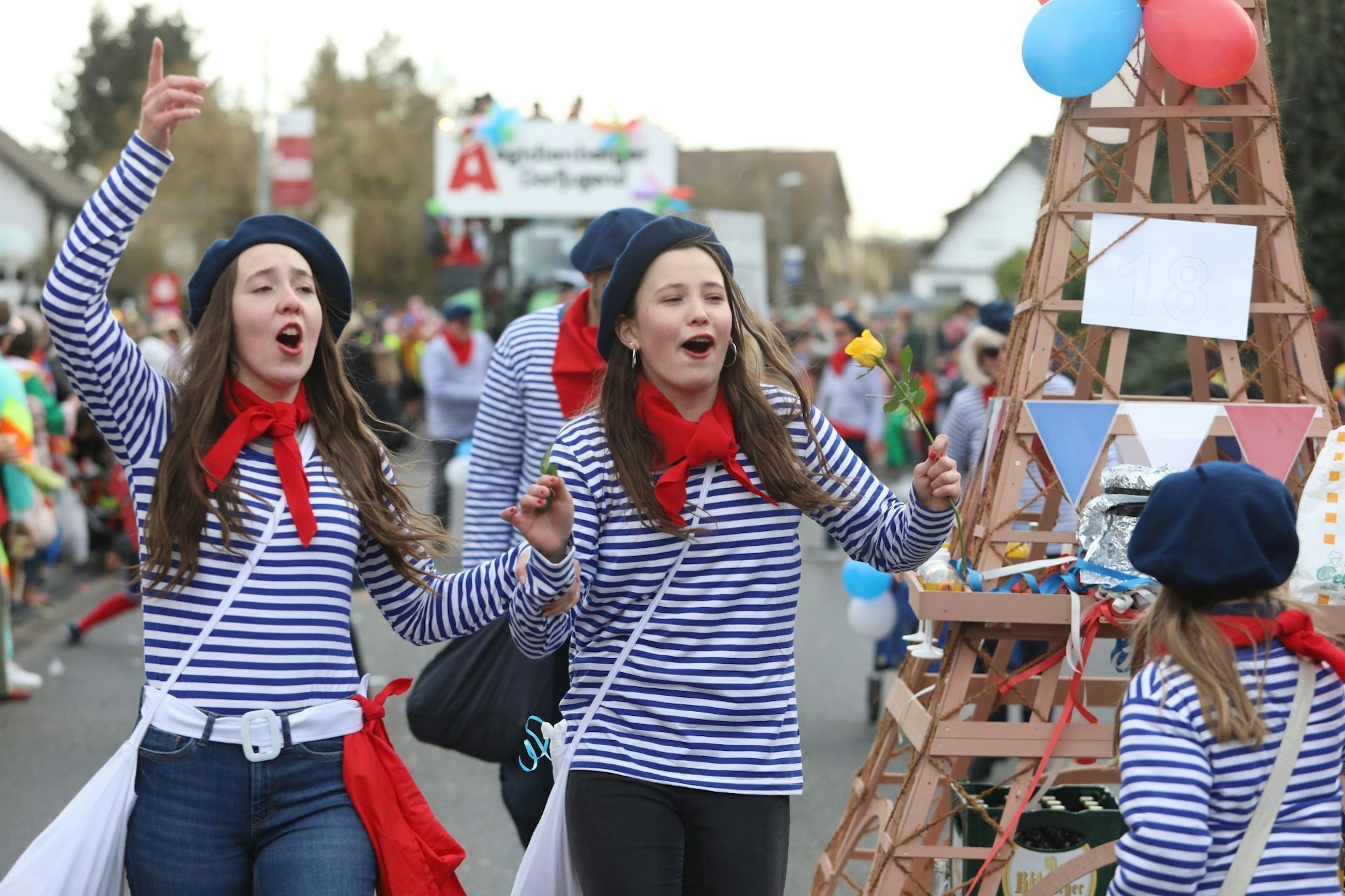 Zwei junge Frauen in blau-weiß gestreiften Pullovern neben einem Eiffelturm aus Holz.