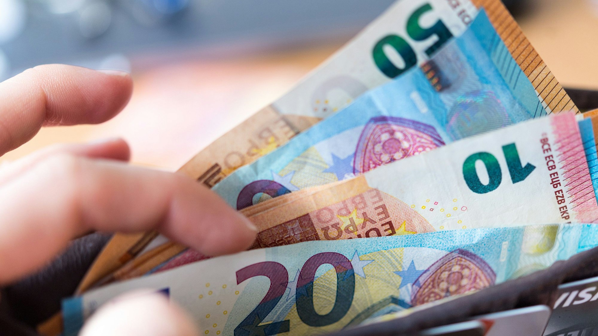 Eine Frau hält eine Geldbörse mit Banknoten in der Hand.