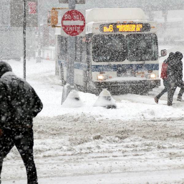 Passanten gehen bei starkem Schneefall über eine Straße in New York, im Hintergrund fährt ein Bus durch den massiven Schneefall. (Archivbild)