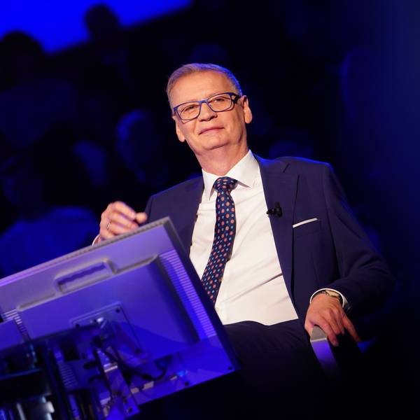 „Wer wird Millionär“-Moderator Günther Jauch sitzt während der Quizshow des Kölner TV-Senders RTL auf seinem Stuhl am Pult uns grinst ins Publikum.
