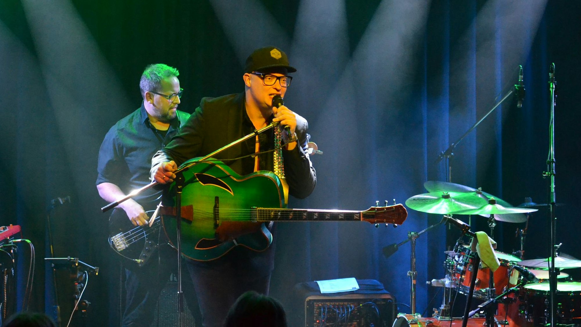 Gitarrist und Sänger Torsten Goods steht auf der Bühne am Mikrofon, dahinter ist der Bassist der Band zu sehen.