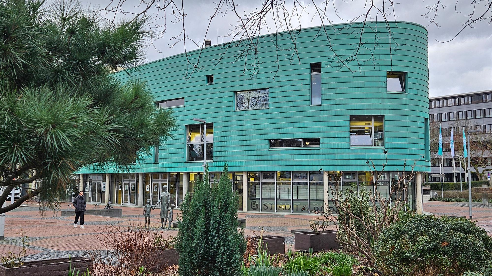 Ein großes Gebäude in der Form eines Schiffbugs mit grüner Fassade.