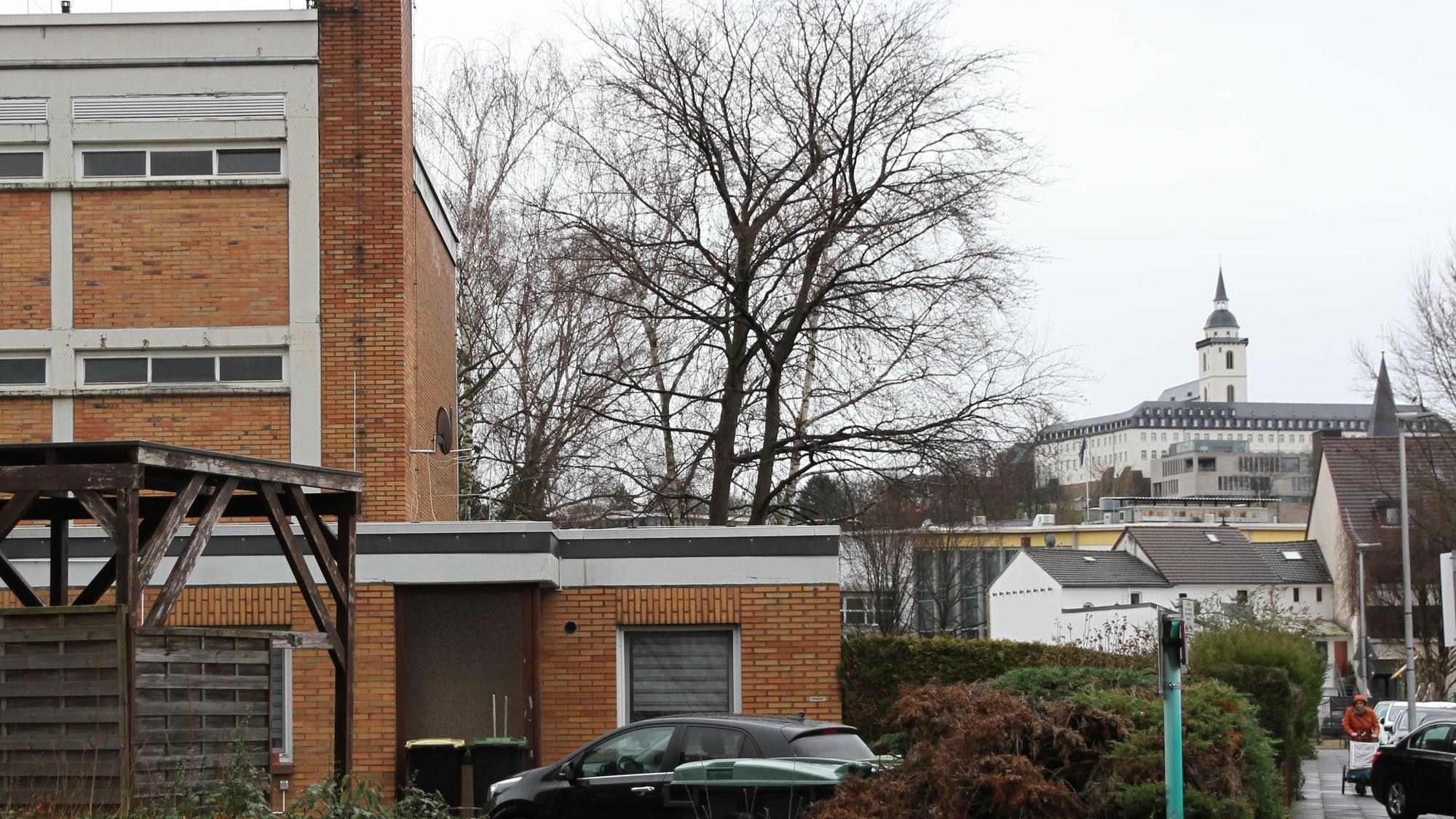 Ein beige verklinkertes Schulgebäude, im Hintergrund die Abtei auf dem Michaelsberg