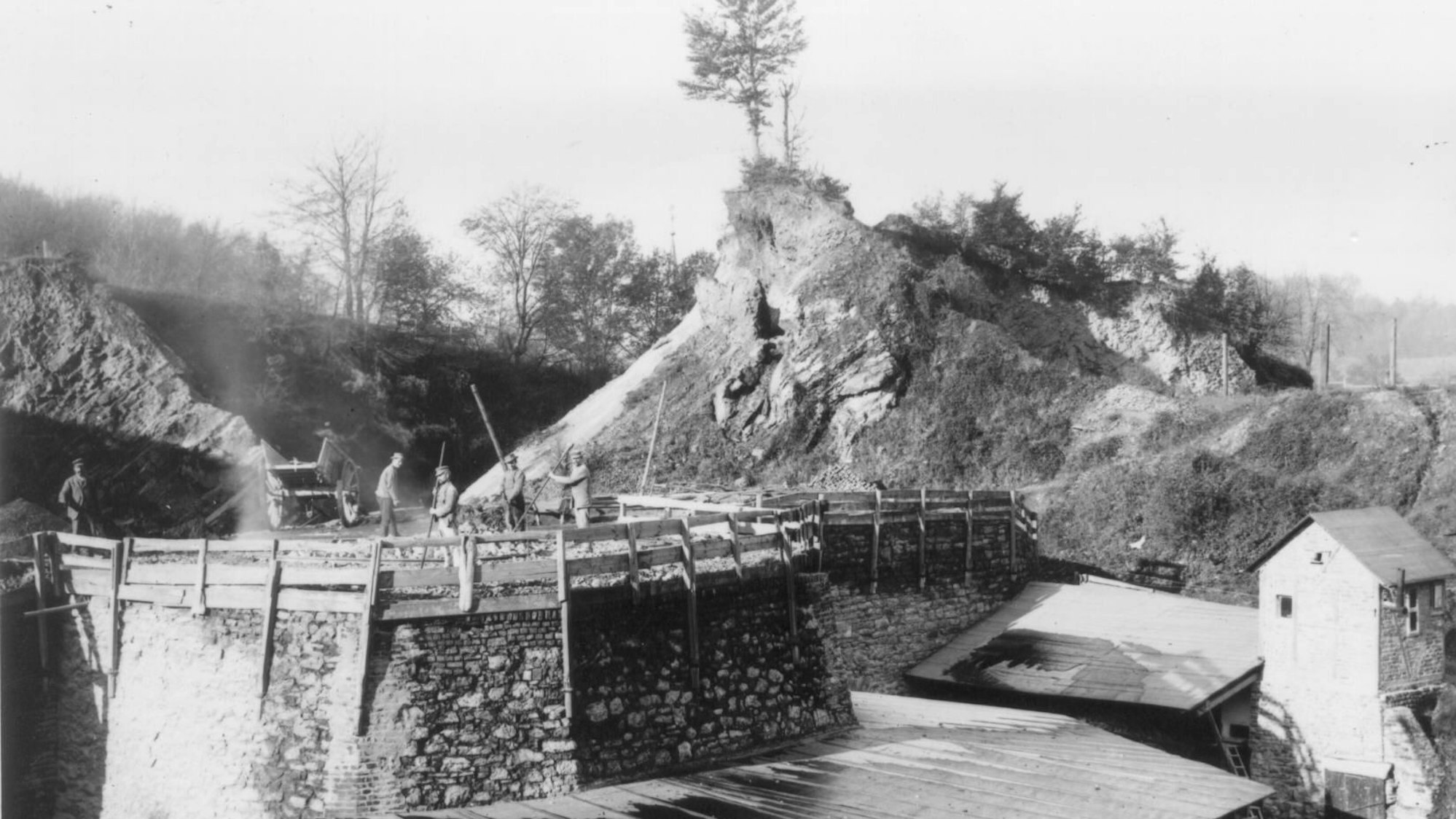 Männer befüllen einen Kalkofen. Historisches Foto um 1890. Im Hintergrund die Turmspitze der evangelischen Gnadenkirche.