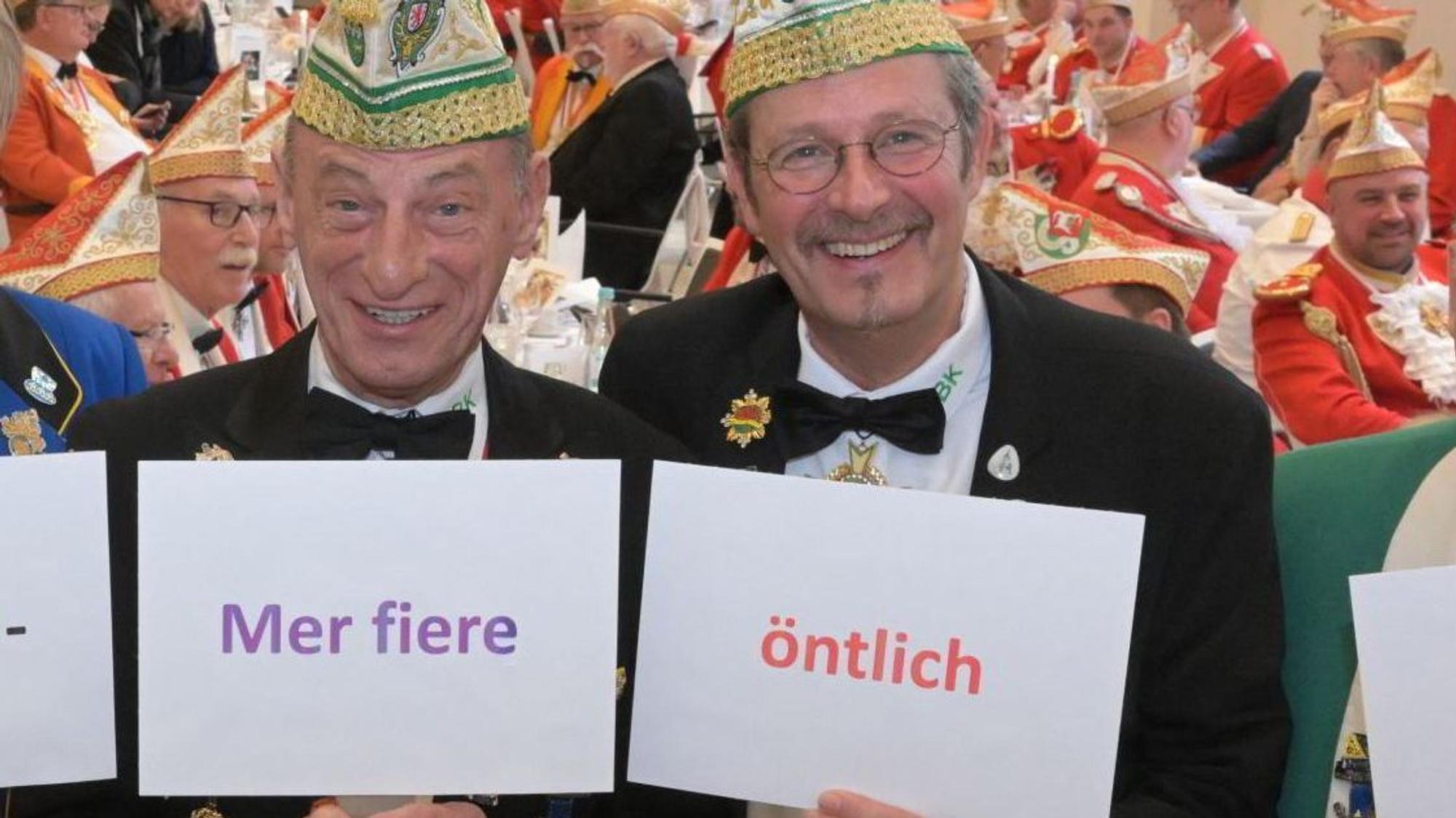 Zwei Männer halten Schilder mit Wörtern in die Höhe.