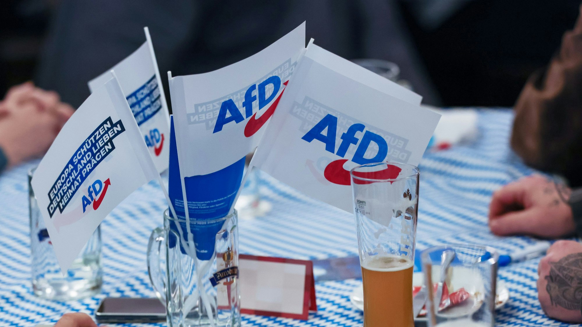 Osterhofen: Beim Politischer Aschermittwoch der AfD stehen Fahnen der Partei auf dem Biertisch.