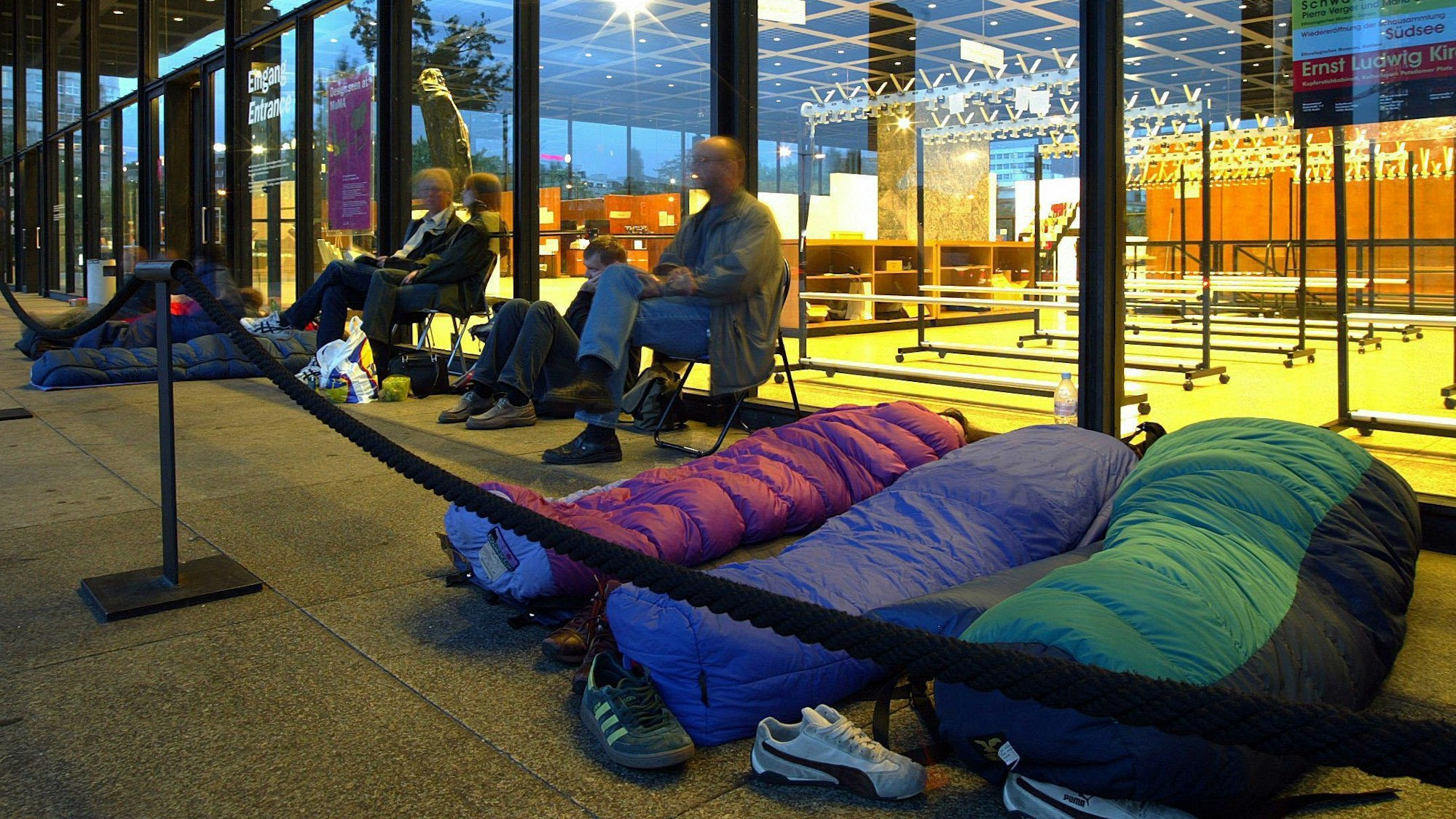 27.08.2004, Berlin: In ihren Schlafsäcken liegend und auf Stühlen sitzend warten Besucher in den frühen Morgenstunden in Berlin auf den Einlass zur Ausstellung des Museum of Modern Art (MoMA) in der Neuen Nationalgalerie.
