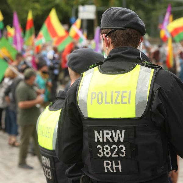 Im Sommer 2021 hatten Kurden auf dem Ottoplatz in Deutz demonstriert. Nun steht eine Großkundgebung auf dem Ottoplatz an. Zu sehen ist ein Polizist und Demonstrierende mit Fahnen.