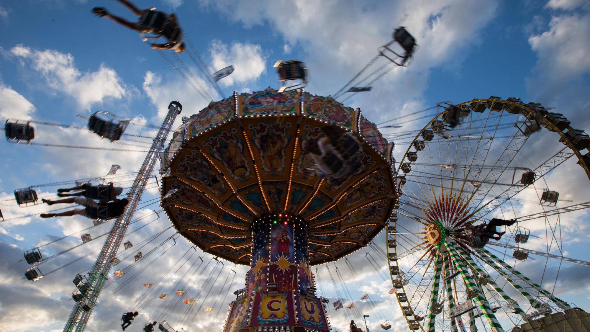 Ein Kettenkarussell dreht sich auf einer Kirmes im Licht der untergehenden Sonne.