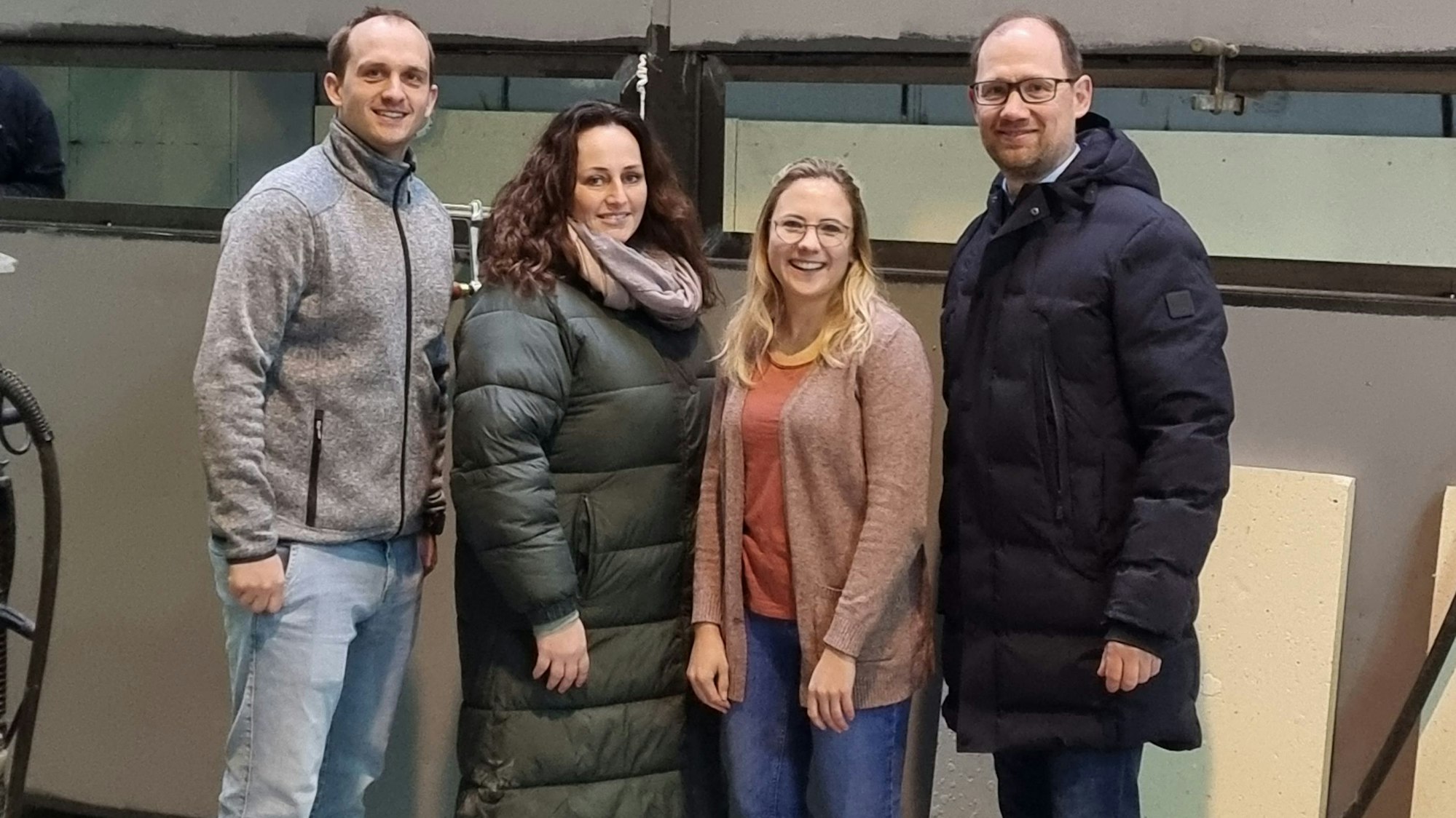 Die vier Personen stehen vor einem künftigen Schwimmcontainer.