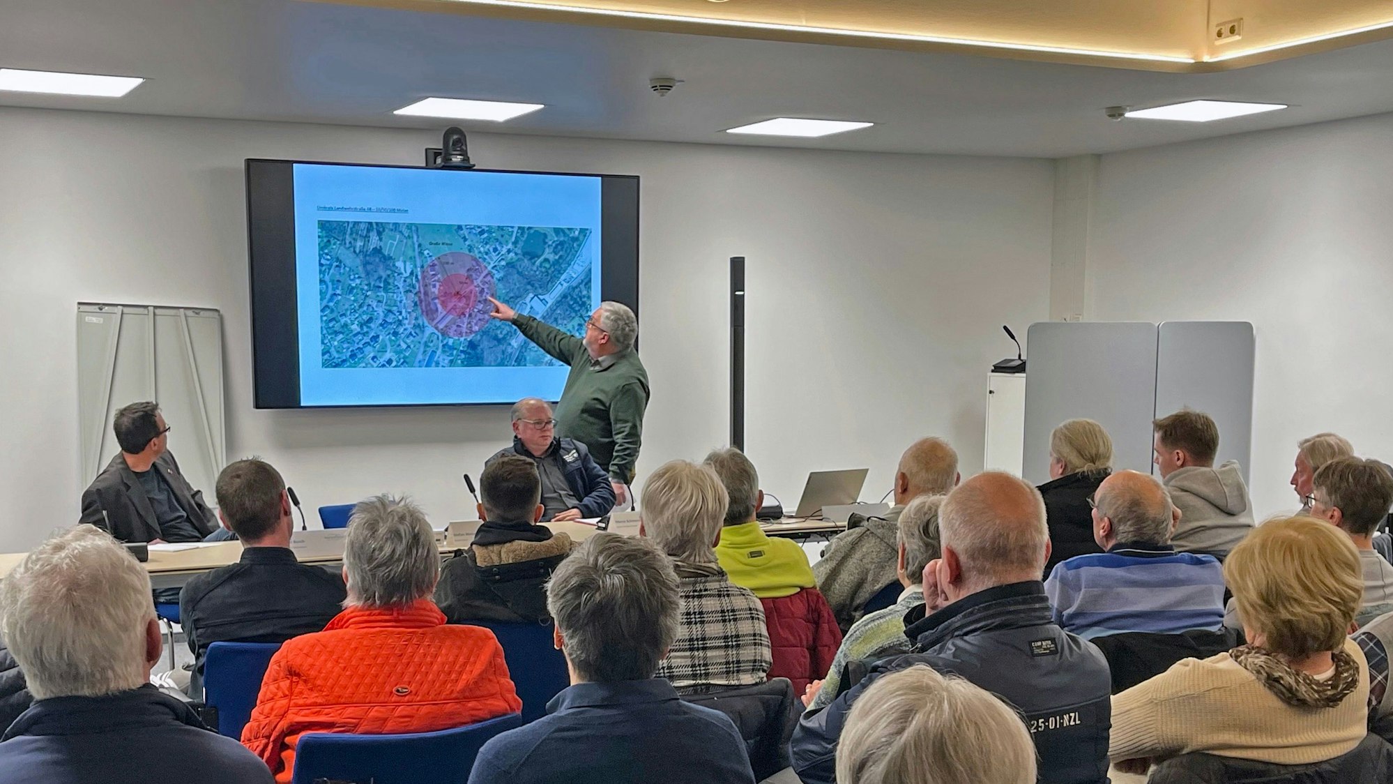 Auf einem Lageplan zeigt Bürgermeister Stefan Meisenberg bei einem Informationsabend den Standort der Container für Geflüchtete.